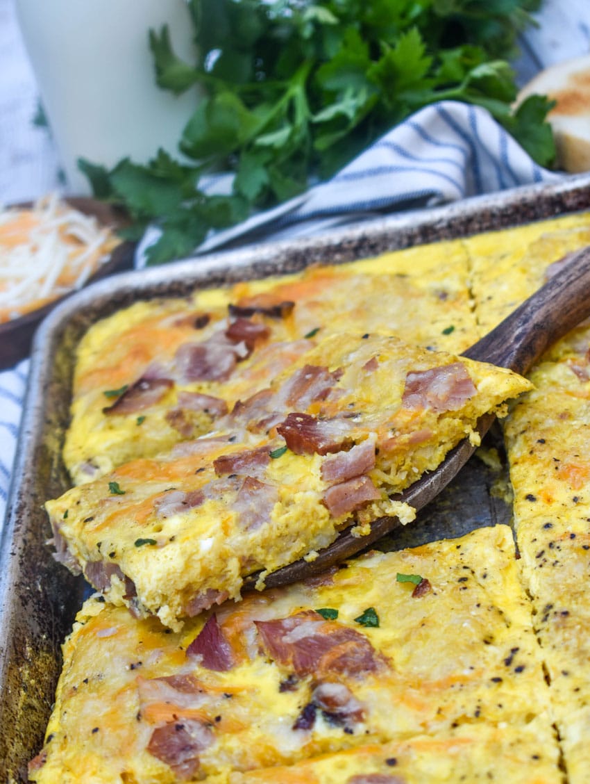 a wooden spatula lifting up a slice of sheet pan breakfast casserole