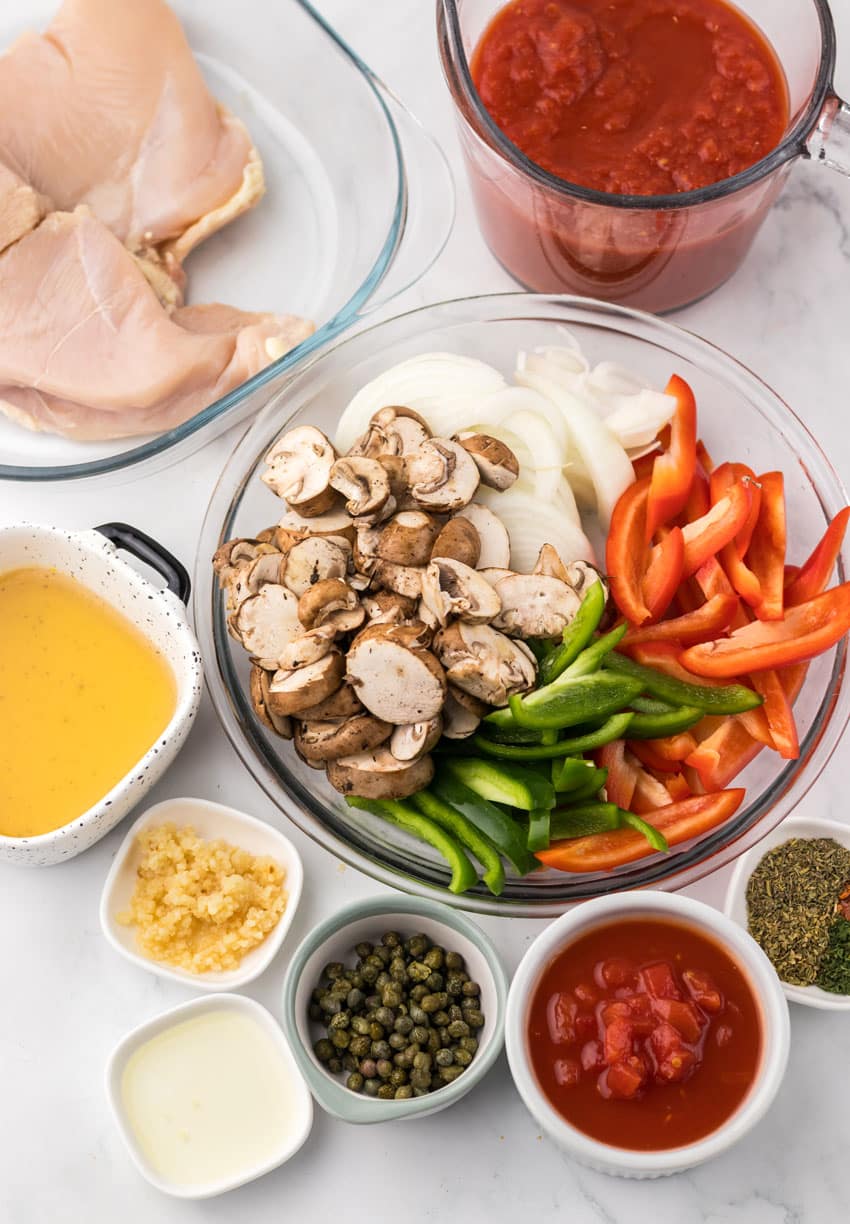an overhead image showing the measured ingredients needed to make a batch of easy chicken cacciatore in the slow cooker