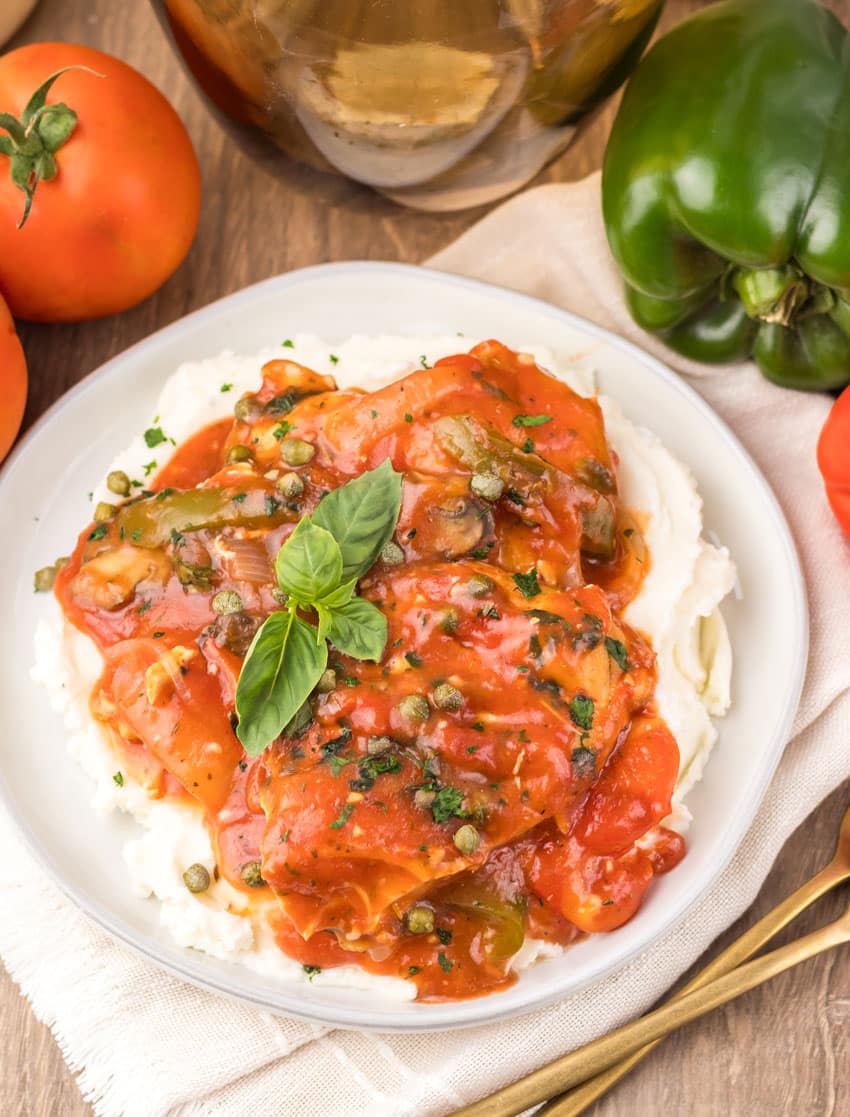 slow cooker chicken cacciatore over mashed potatoes on a white plate