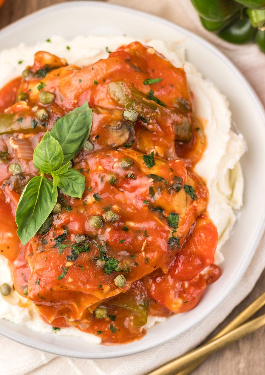slow cooker chicken cacciatore over mashed potatoes on a white plate