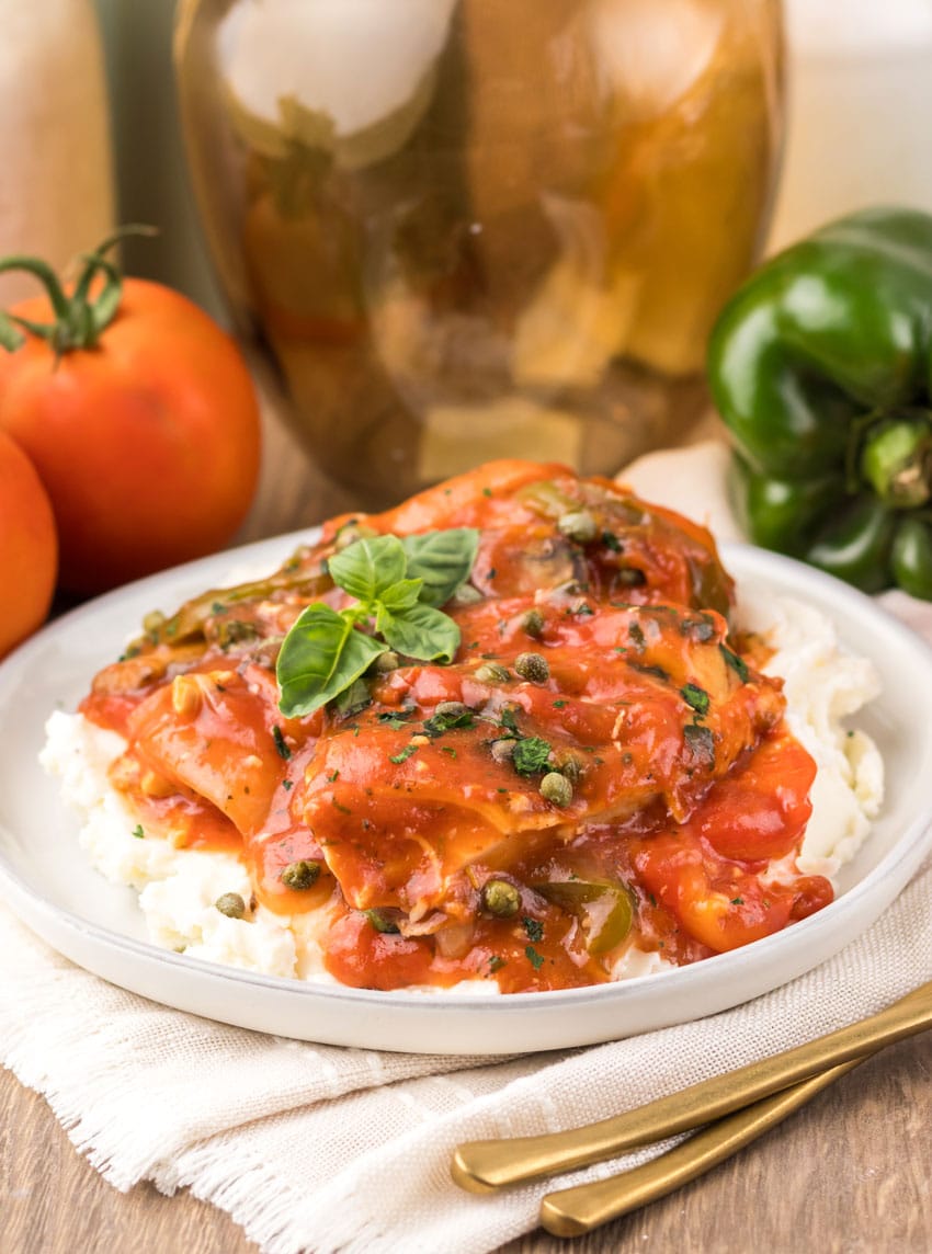 slow cooker chicken cacciatore over mashed potatoes on a white plate