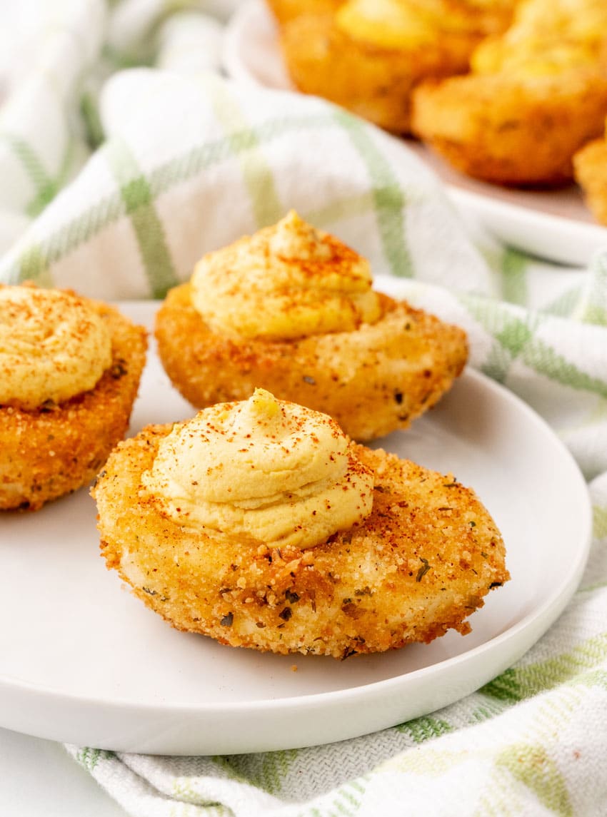 three deep fried deviled eggs on a small white appetizer plate