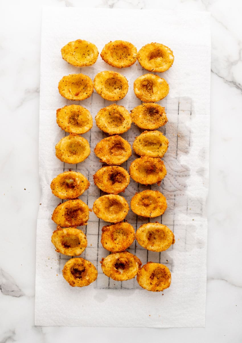 breaded and fried egg shells draining on a paper towel lined wire rack