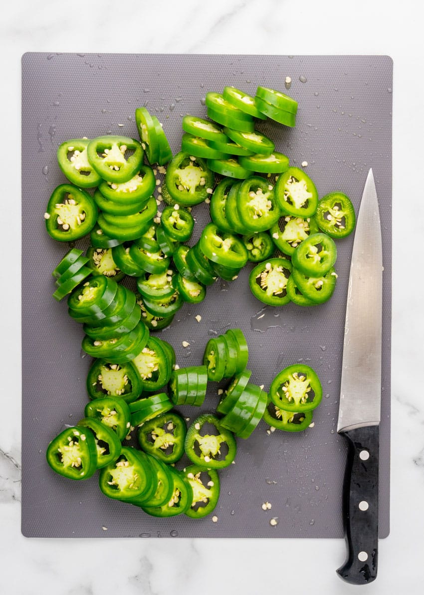 thinly sliced jalapeno peppers on a gray cutting board