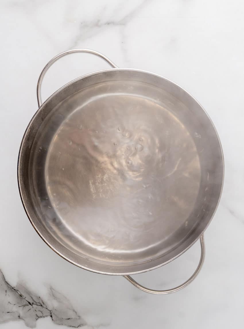 a steaming hot homemade pickle brine in a metal pot on a marble counter