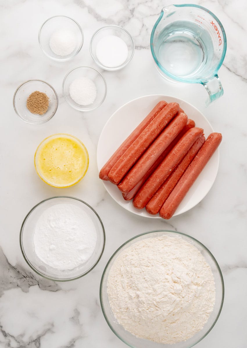 an overhead image showing the measured ingredients needed to make a batch of homemade pretzel dogs