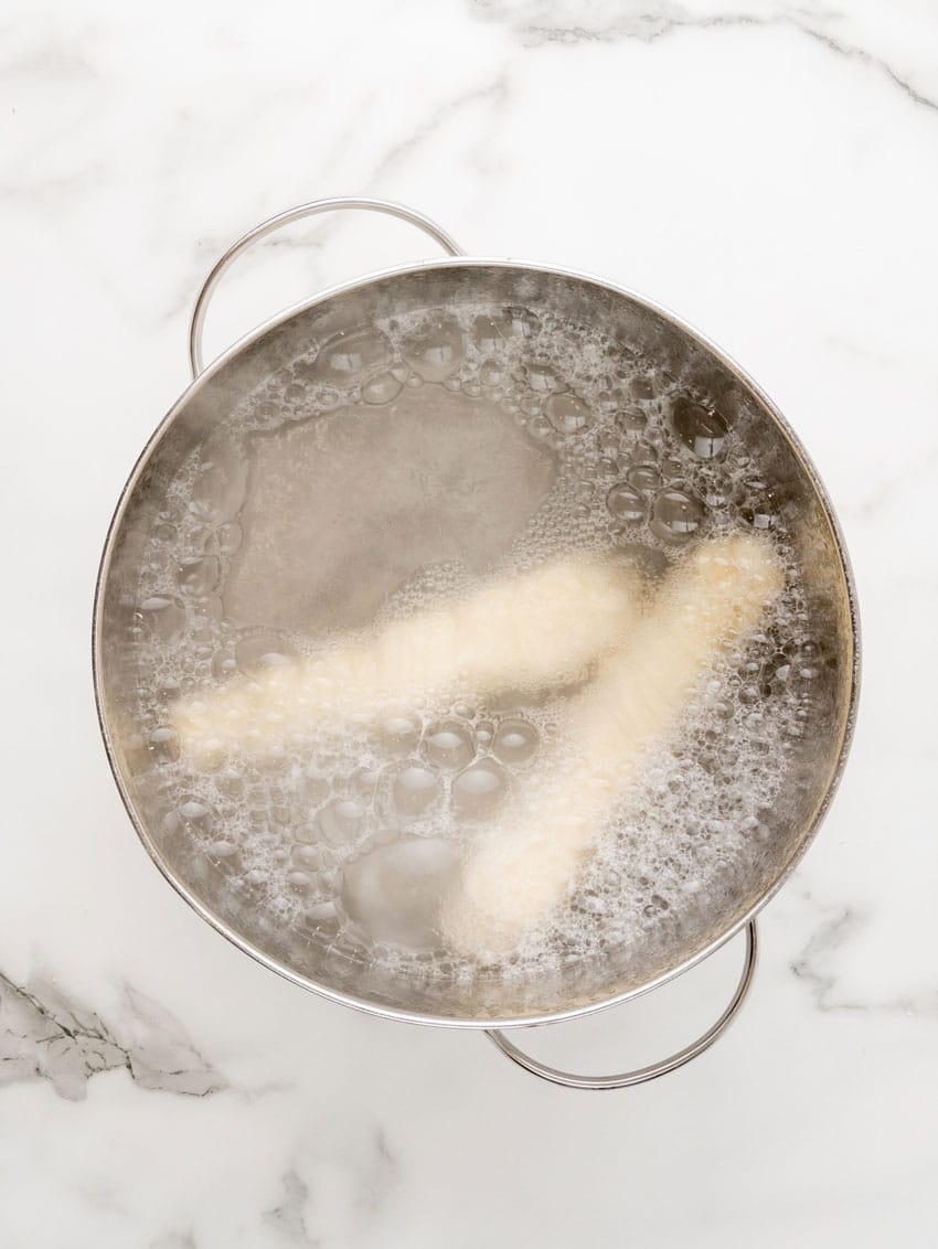 two copycat pretzel dogs boiling in a pot of water