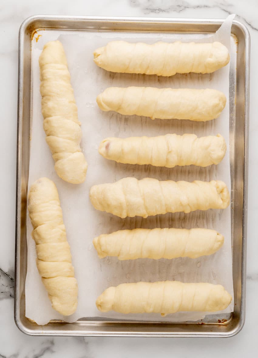 boiled copycat pretzel dogs arranged in two rows on a parchment paper lined baking sheet