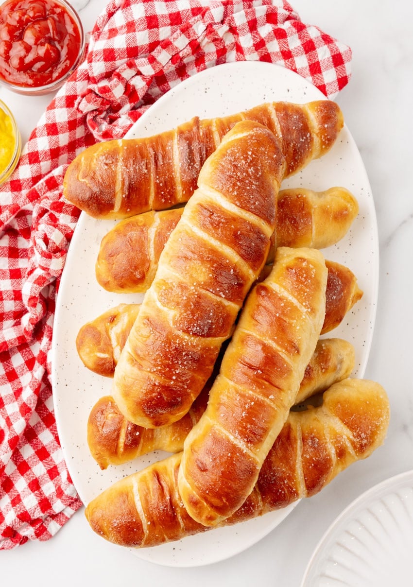 homemade pretzel dogs stacked on a white serving platter
