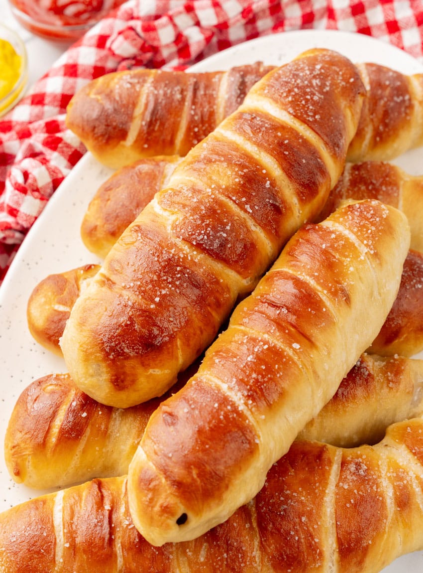 homemade pretzel dogs stacked on a white serving platter
