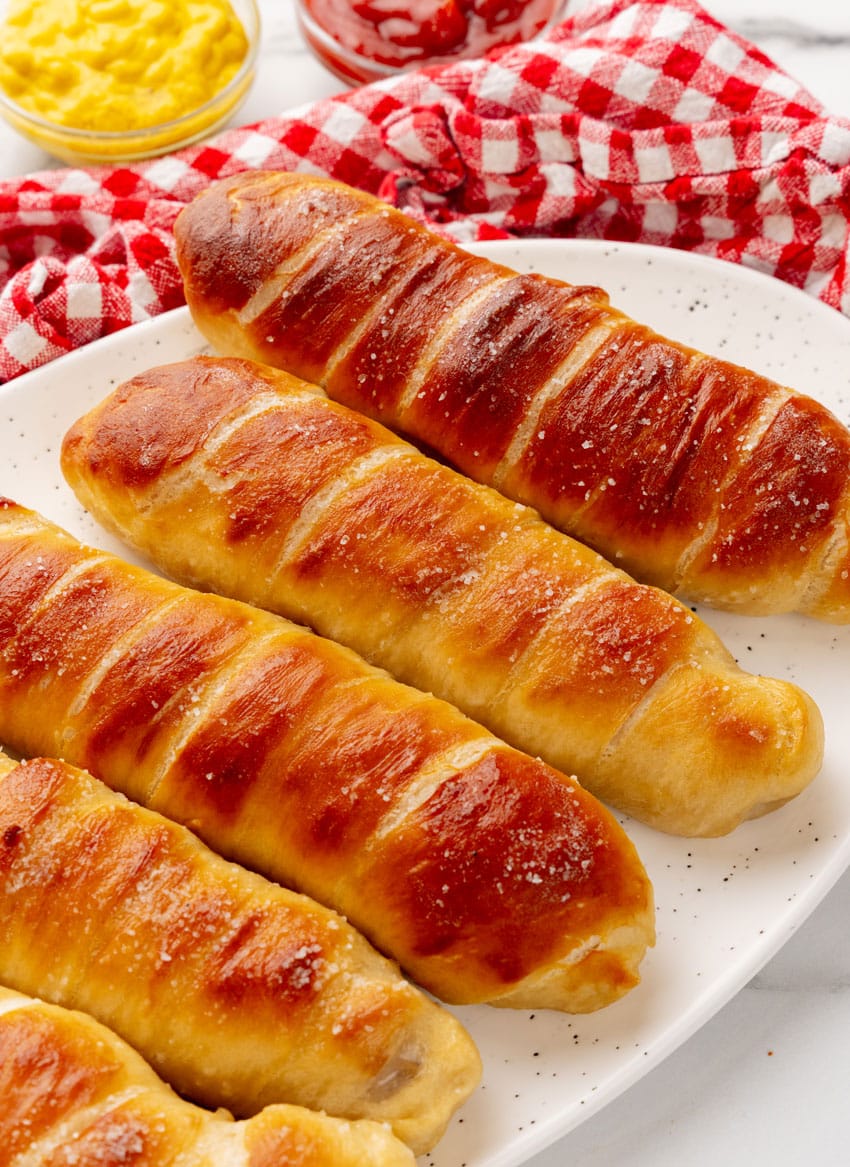 homemade pretzel dogs stacked on a white serving platter