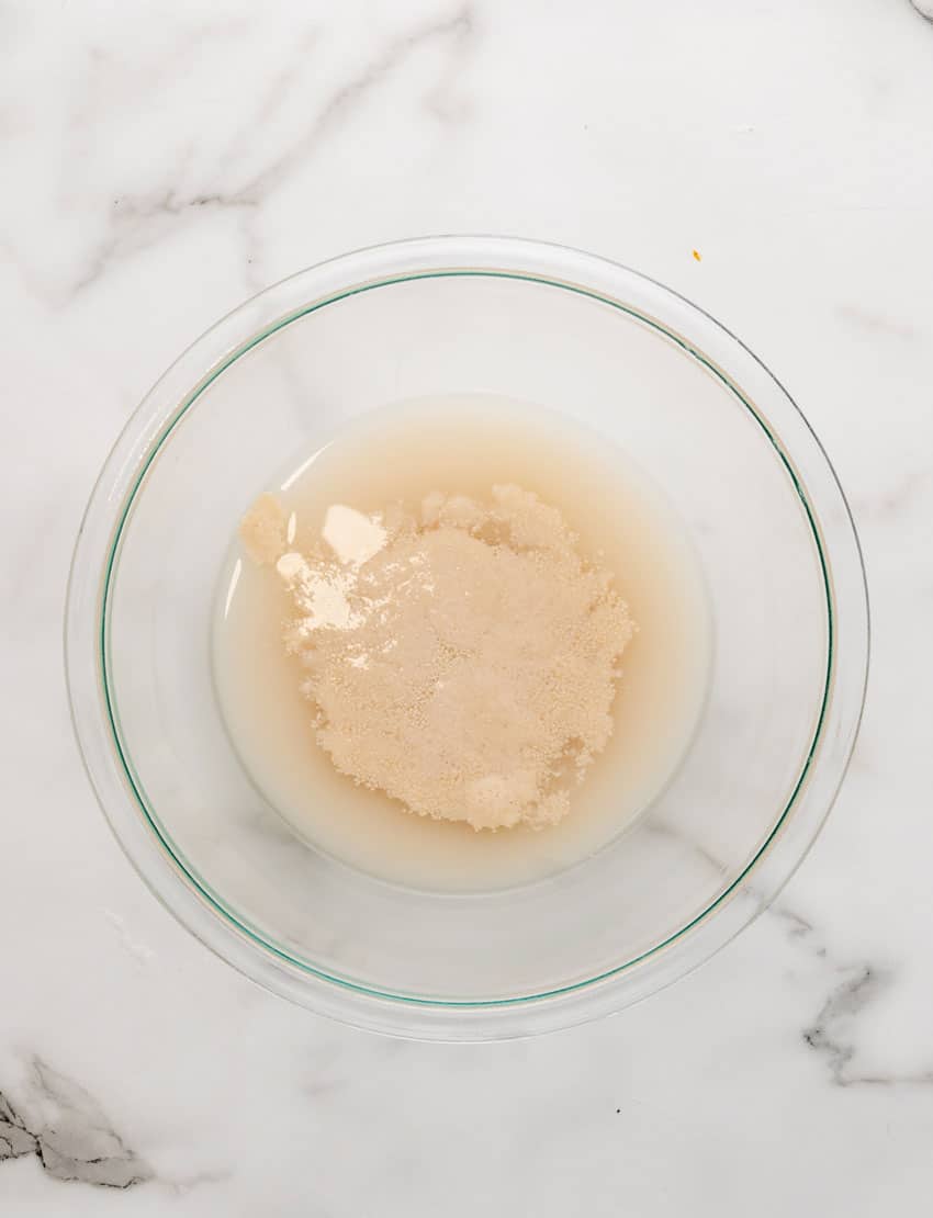 yeast blooming in warm water in a glass mixing bowl