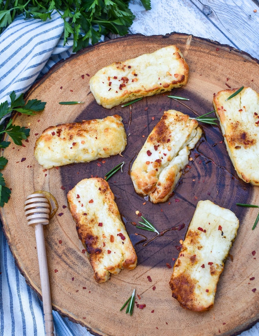 slices of air fried halloumi cheese on a wooden cutting board