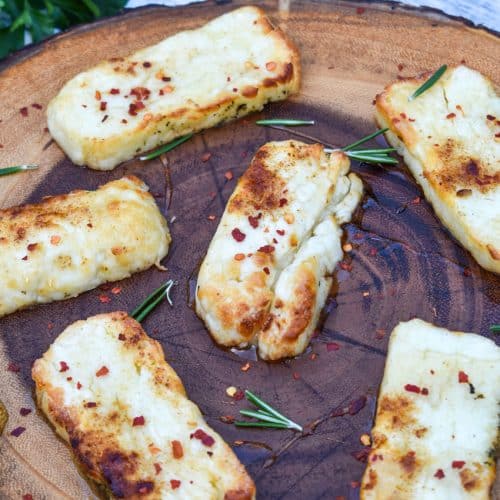 slices of air fried halloumi cheese on a wooden cutting board