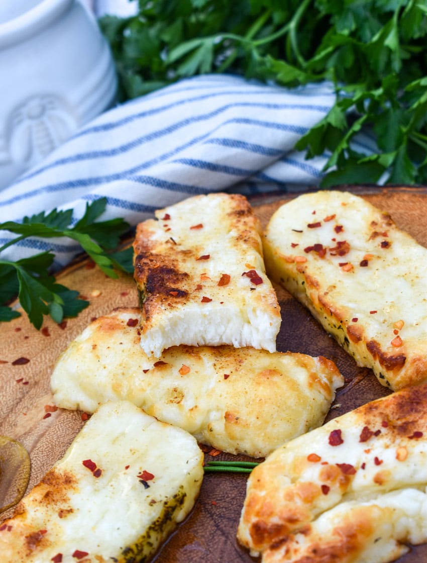 slices of air fried halloumi cheese on a wooden cutting board