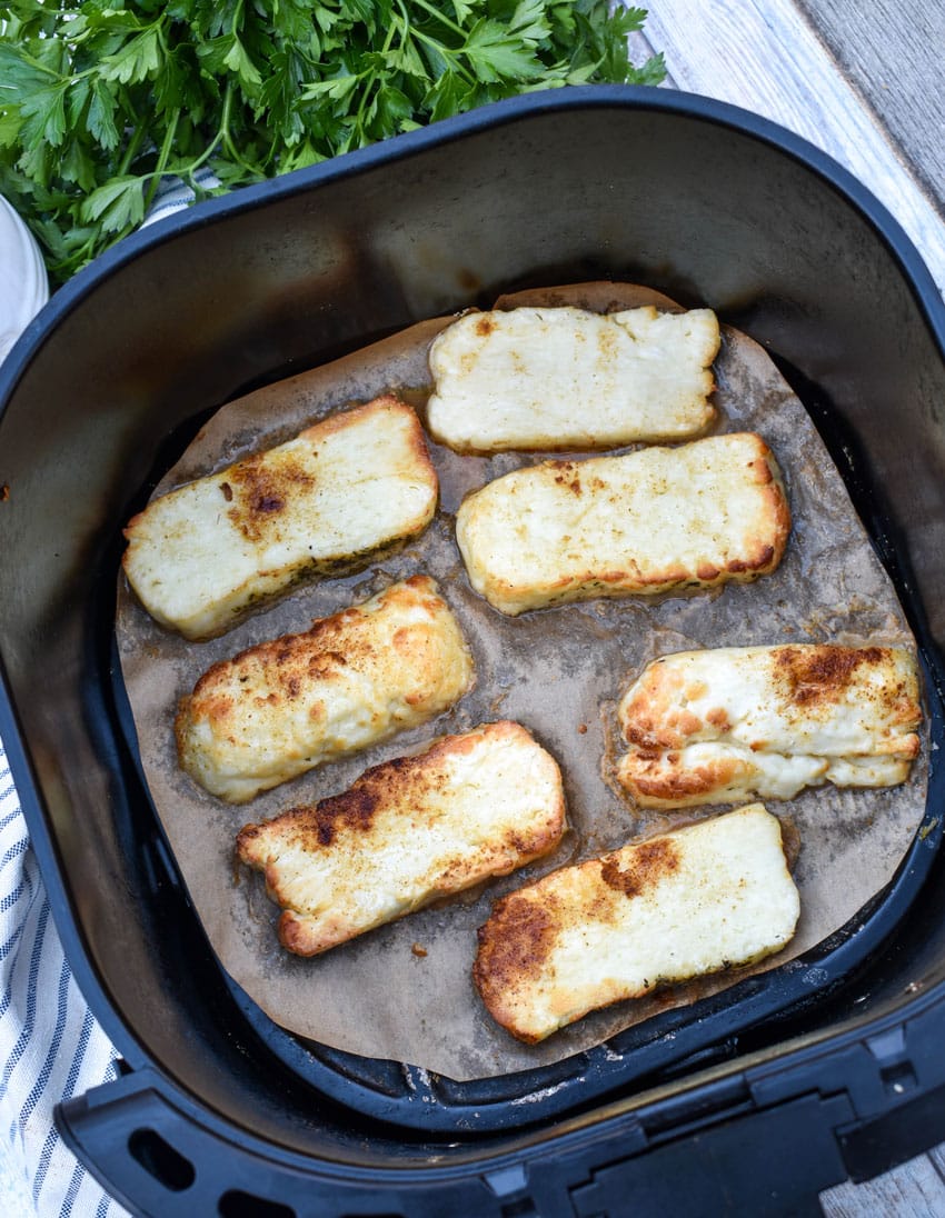 slices of crispy halloumi cheese in the basket of an air fryer