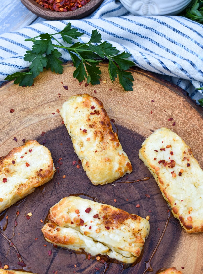 slices of air fried halloumi cheese on a wooden cutting board