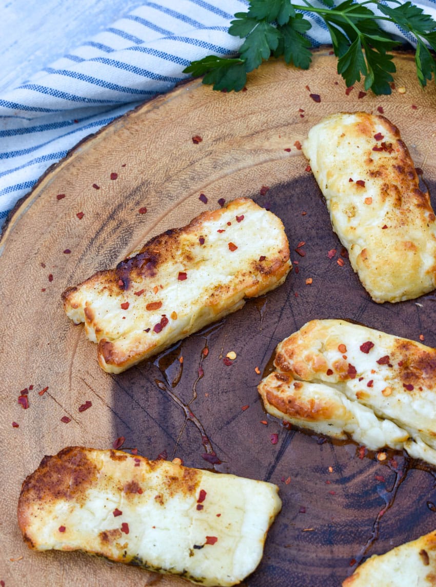 slices of air fried halloumi cheese on a wooden cutting board