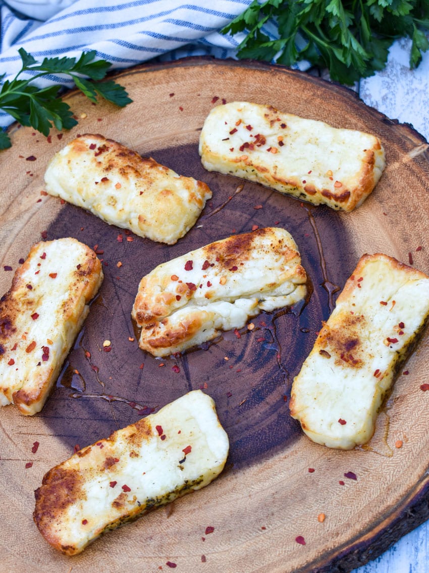 slices of air fried halloumi cheese on a wooden cutting board