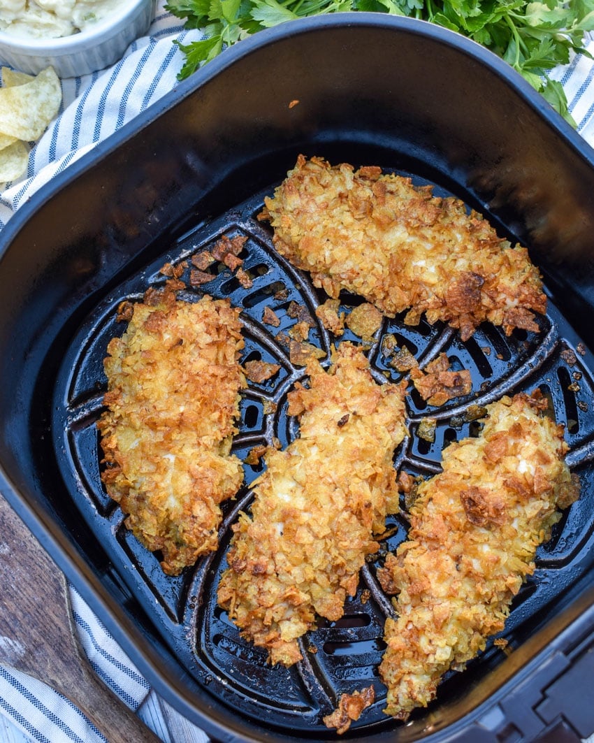 crispy potato chip coated chicken strips in the basket of an air fryer