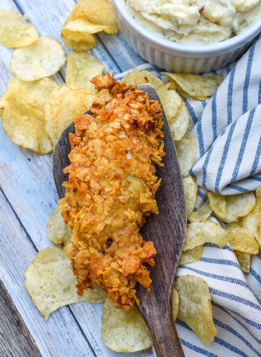 an air fried potato chip chicken strips resting on a wooden spatula