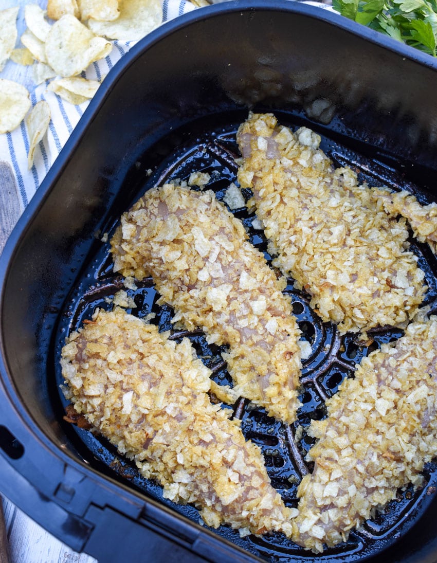 crunchy potato chip coated strips of chicken in the basket of an air fryer