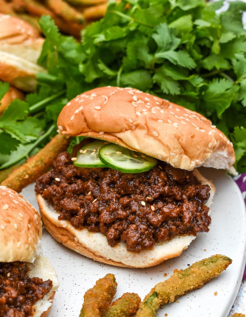 an asian style sloppy joe sandwich and green bean fries on a white serving platter