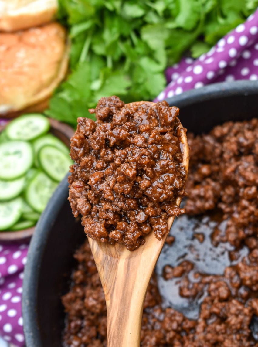 a wooden spoon holding up a scoop of asian sloppy joe meat