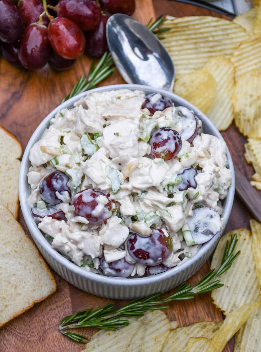 a copycat version of panera bread's napa chicken salad in a small white bowl on a wooden cutting board
