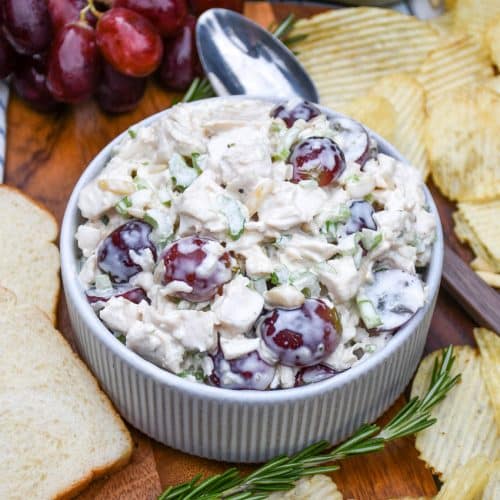 a copycat version of panera bread's napa chicken salad in a small white bowl on a wooden cutting board