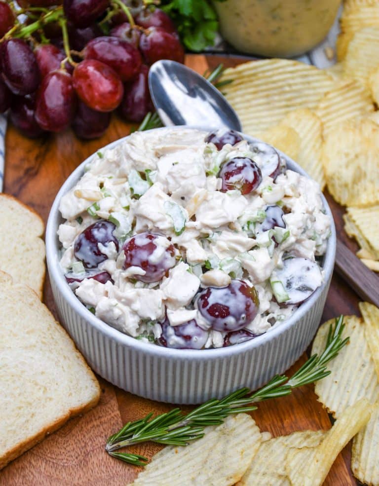 a copycat version of panera bread's napa chicken salad in a small white bowl on a wooden cutting board