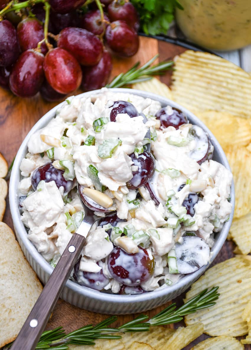 a copycat version of panera bread's napa chicken salad in a small white bowl on a wooden cutting board