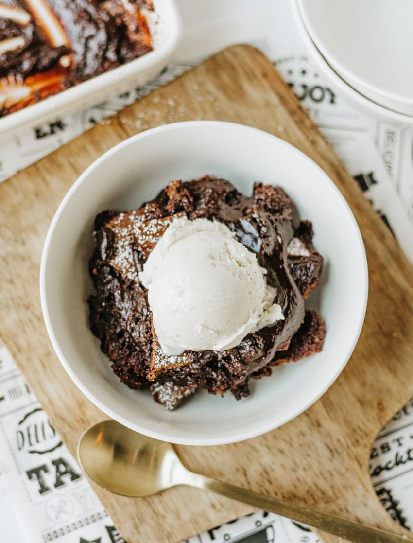 ina garten's brownie pudding topped with a scoop of vanilla ice cream in a white bowl