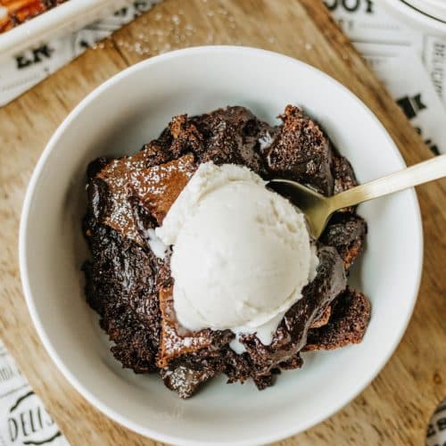 ina garten's brownie pudding topped with a scoop of vanilla ice cream in a white bowl