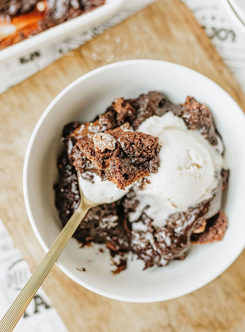 ina garten's brownie pudding topped with a scoop of vanilla ice cream in a white bowl