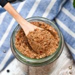 a small wooden spoon scooping homemade montreal steak seasoning out of a small glass jar