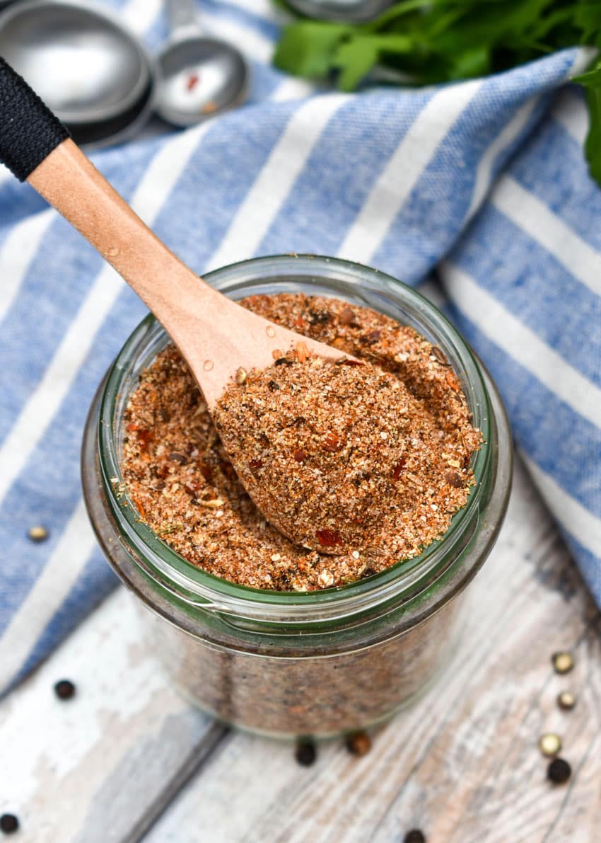 a small wooden spoon scooping homemade montreal steak seasoning out of a small glass jar