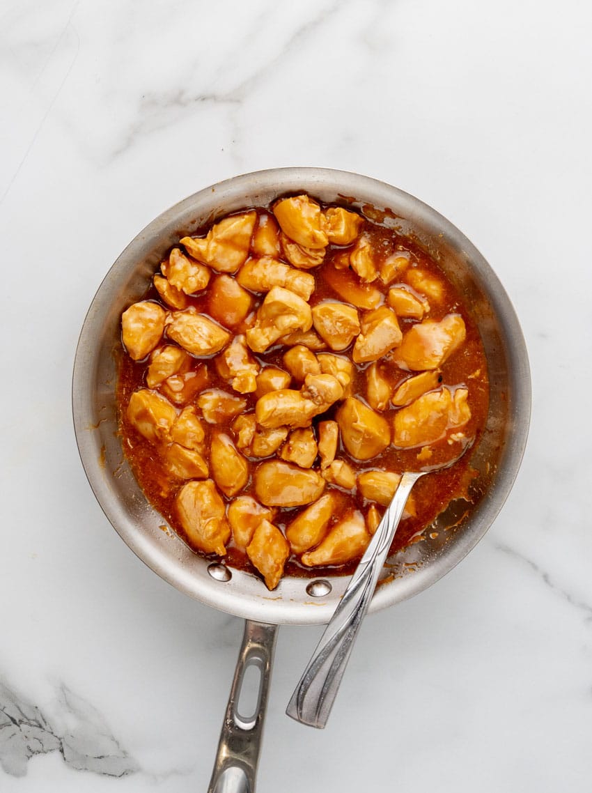 cooked chicken chunks in an asian american sauce in a metal skillet