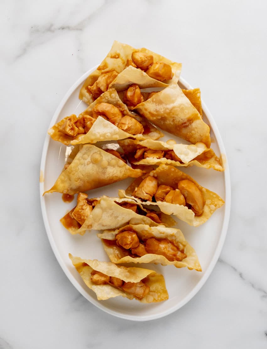 assembled abblebee's copycat chicken wonton tacos arranged in a row on a white serving platter