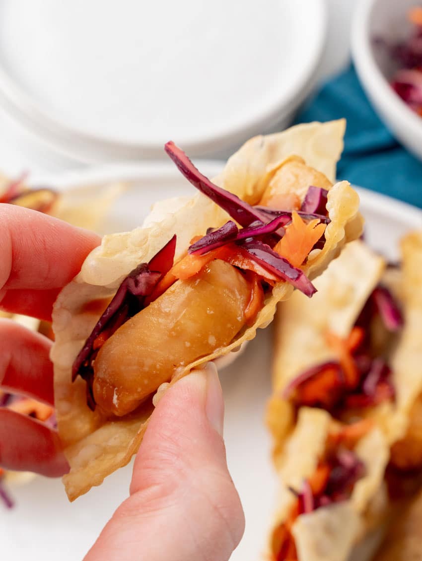 a hand holding up a homemade chicken wonton taco