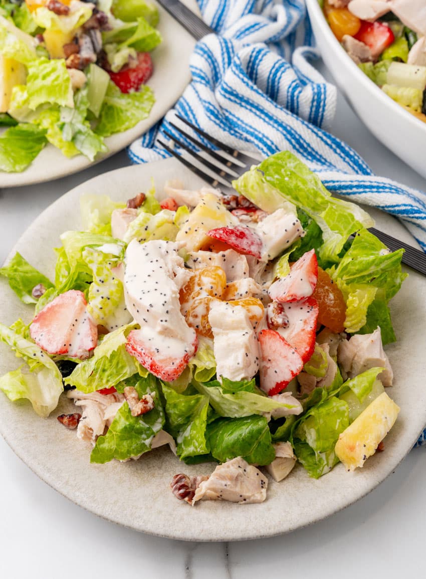 Copycat Panera strawberry poppyseed chicken salad on a small white plate with a black fork resting on the side