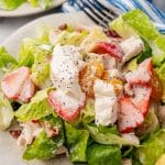 Copycat Panera strawberry poppyseed chicken salad on a small white plate with a black fork resting on the side