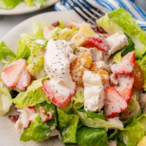 Copycat Panera strawberry poppyseed chicken salad on a small white plate with a black fork resting on the side