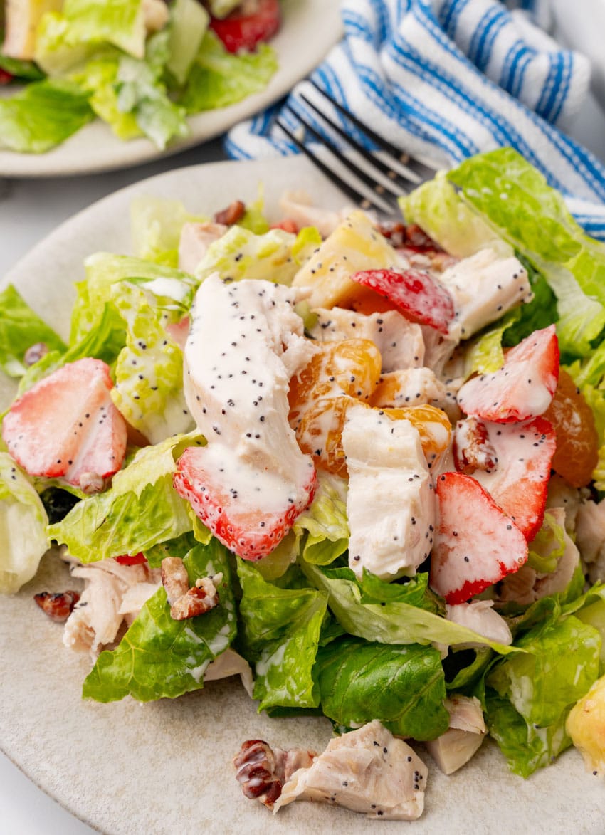 Copycat Panera strawberry poppyseed chicken salad on a small white plate with a black fork resting on the side