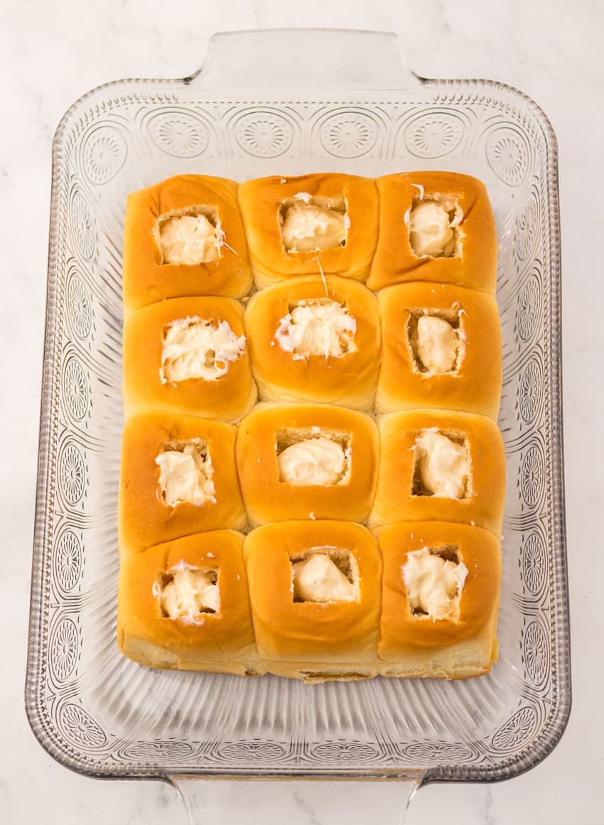 cream cheese stuffed sweet hawaiian rolls in a glass baking dish
