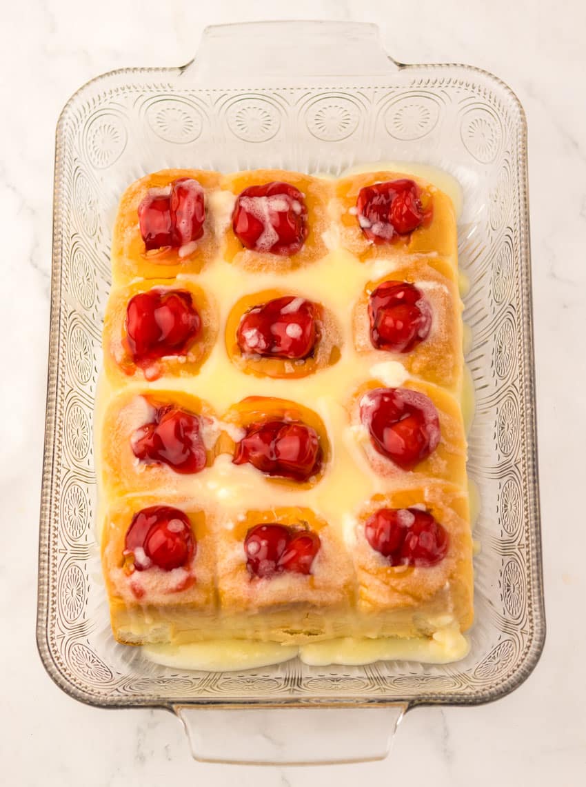 cherry pie filling stuffed sweet hawaiian rolls in a glass baking dish