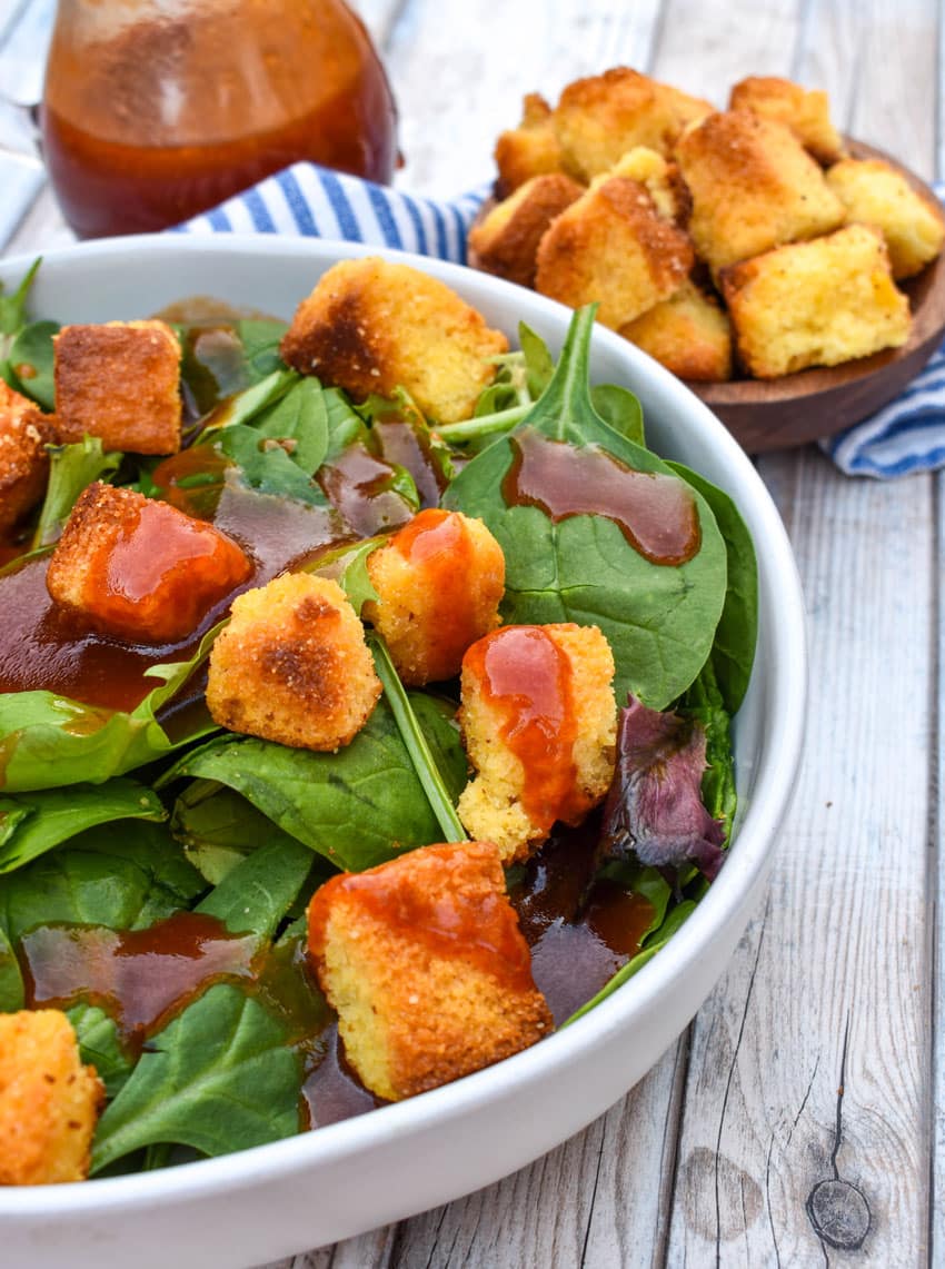 homemade catalina dressing over leafy greens in a shallow white bowl