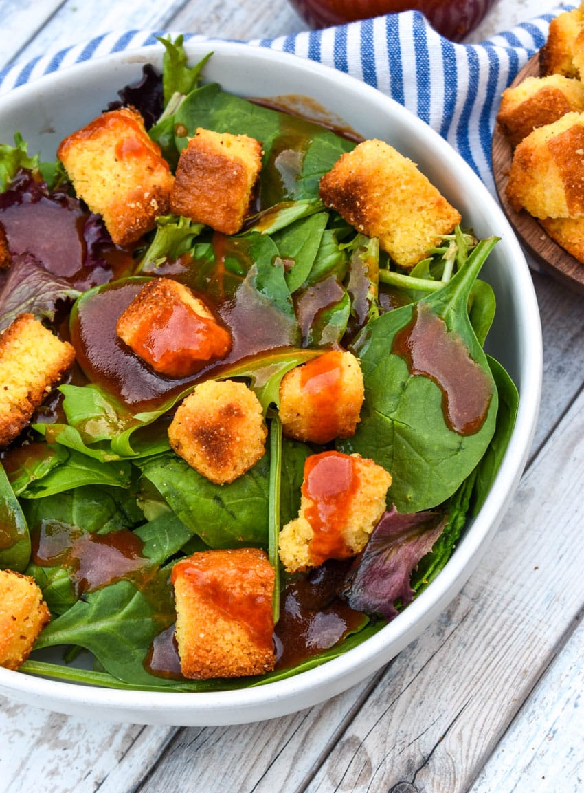 homemade catalina dressing over leafy greens in a shallow white bowl