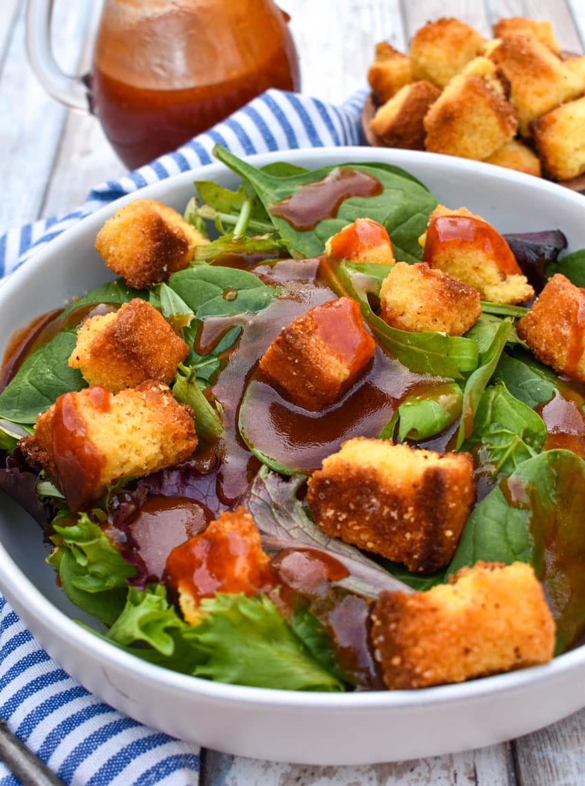 homemade catalina dressing over leafy greens in a shallow white bowl