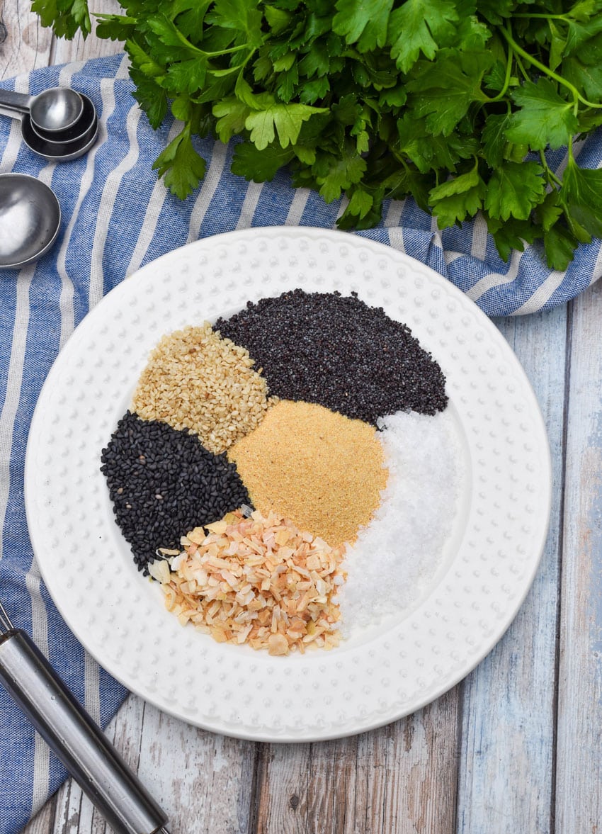 an overhead image showing the measured ingredients needed to make a batch of homemade everything bagel seasoning on a small white plate